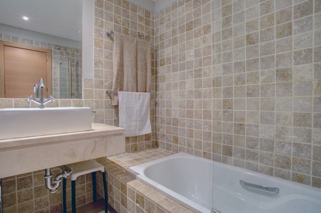 Image shows the bath of the main bathroom and this area has fully tiled walls.