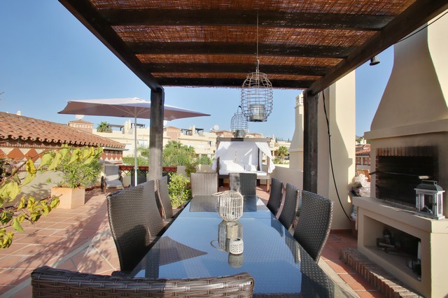 Image shows al fesco dining area with cover and brick built charcoal BBQ