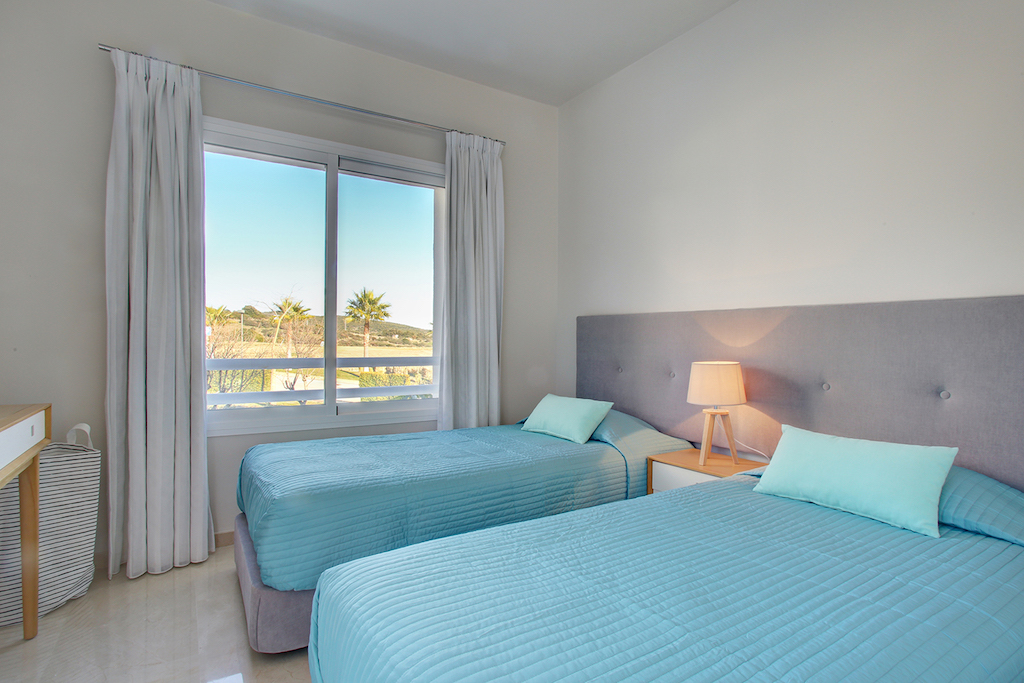 Image shows twin beds and a window with views to mountains