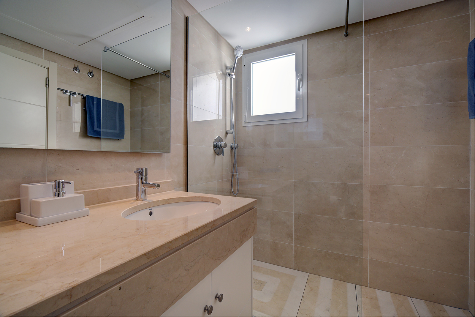 Image shows large marble bathroom with a walk in shower