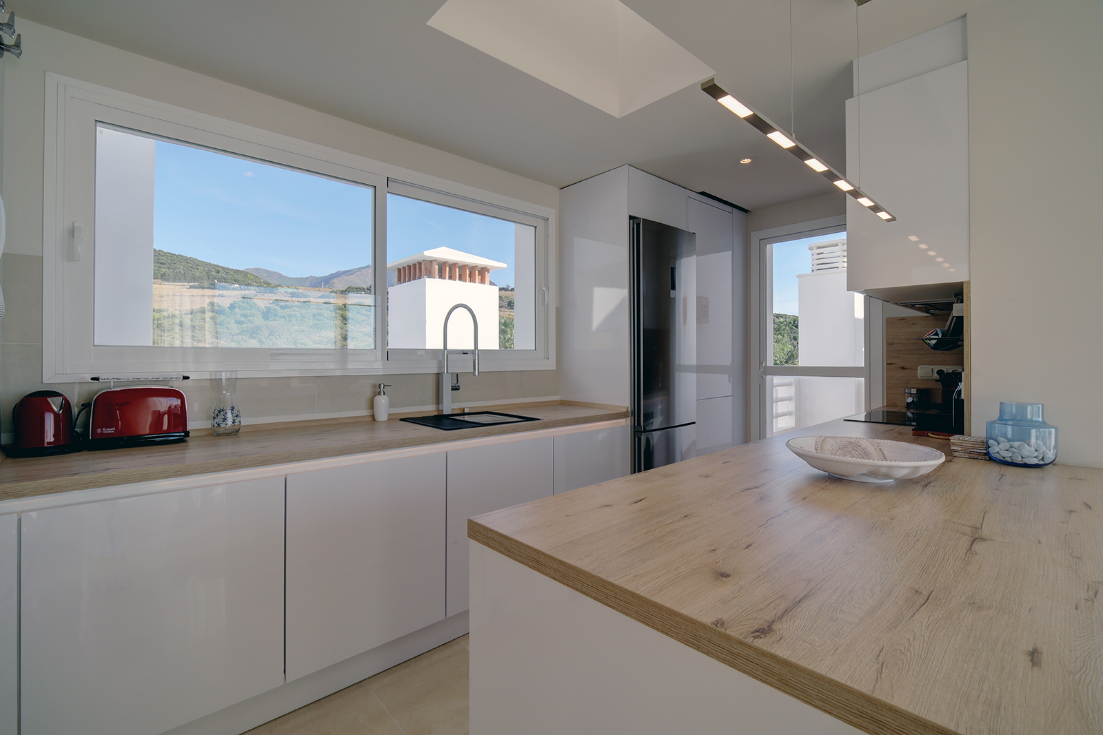 Image shows open kitchen space with window and views to mountains