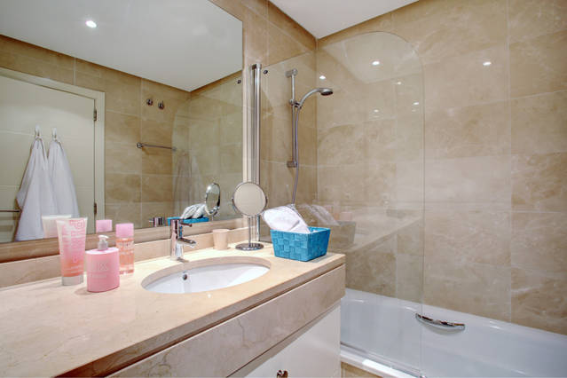 Images shows large marble bathroom with bath tub and showe