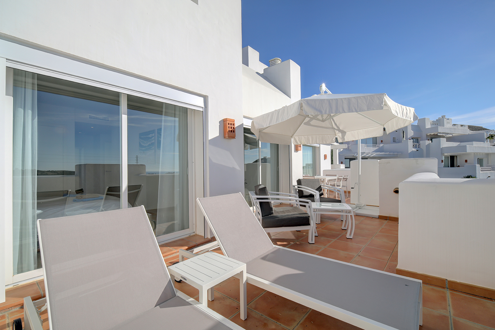 Image shows terrace with 2 sunbeds and dinnig table