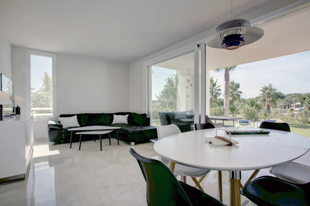 Image shows large modern living room with dining area and terraces