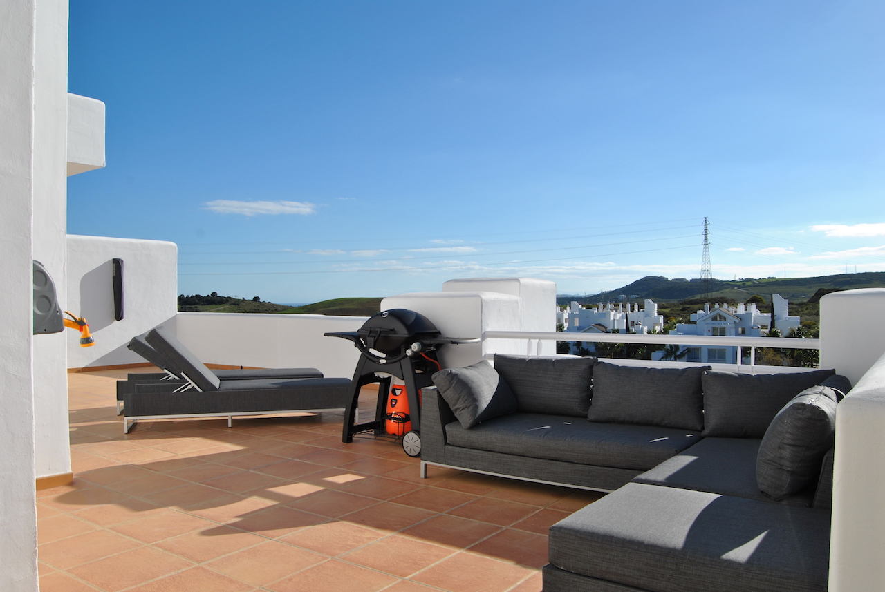 Image shows large terrace sunloungers and a weber BBQ