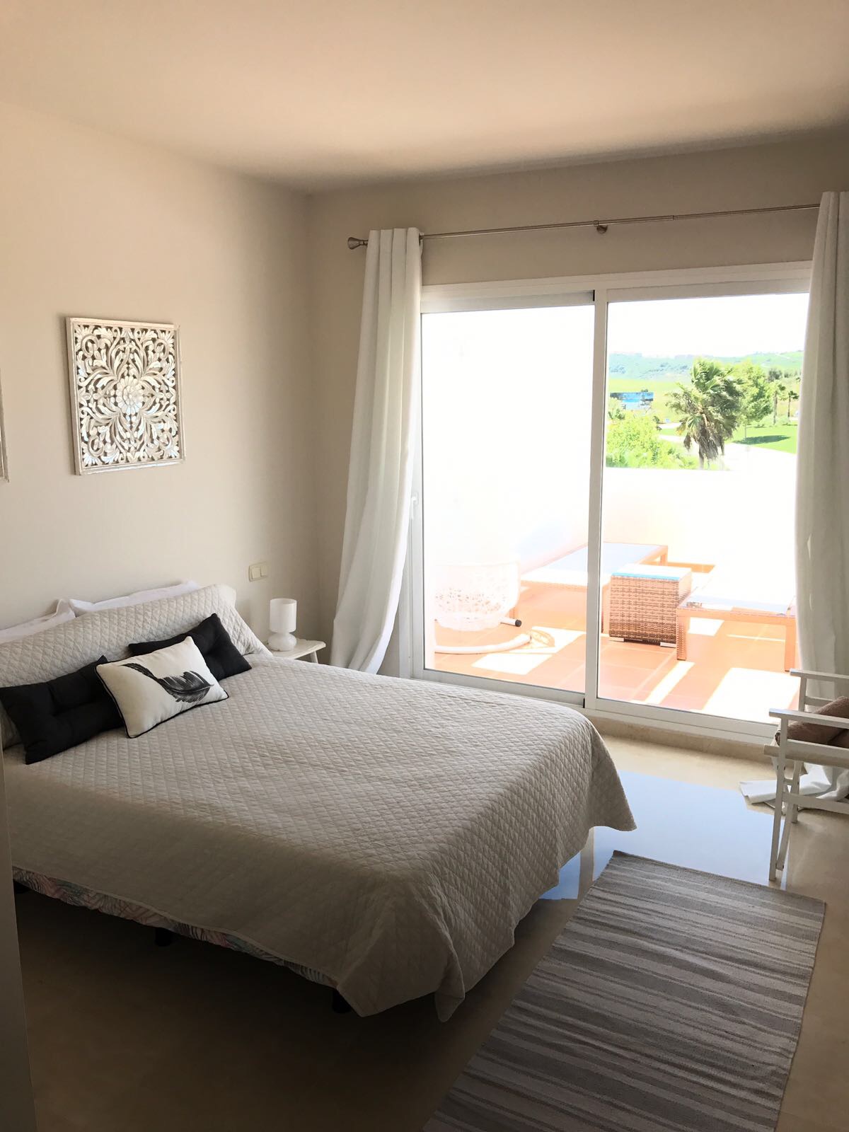 Image shows the main bedroom of this stylish penthouse in Alcazaba Lagoon with a large double bed and access to the terrace